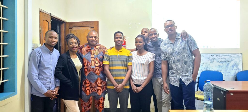 A group of 8 African scholars stand at the front of a classroom, smiling at the camera