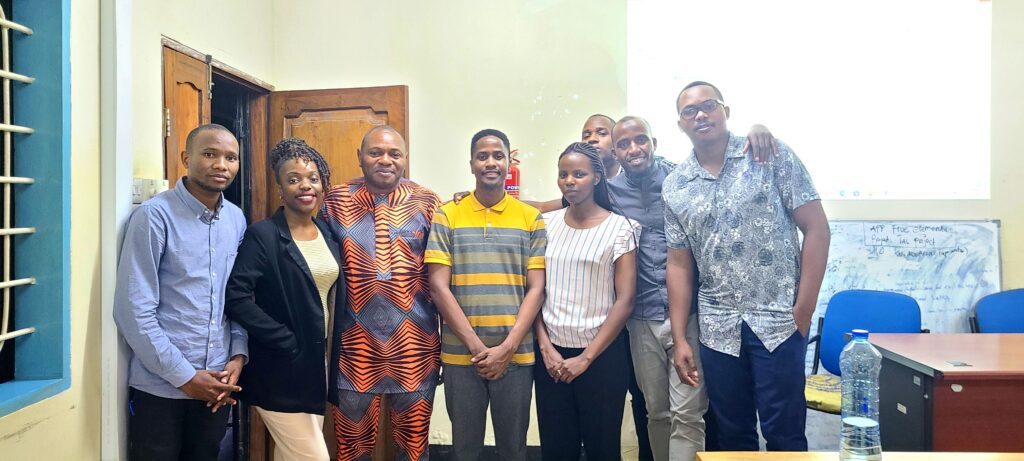 A group of 8 African scholars stand at the front of a classroom, smiling at the camera