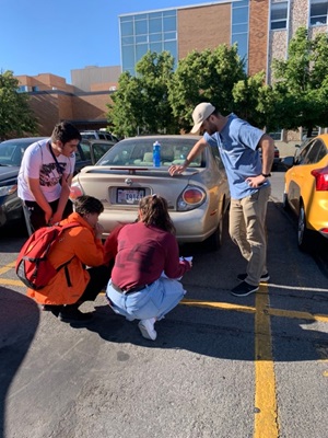 Students and teacher gather to test emissions from a car tailpipe