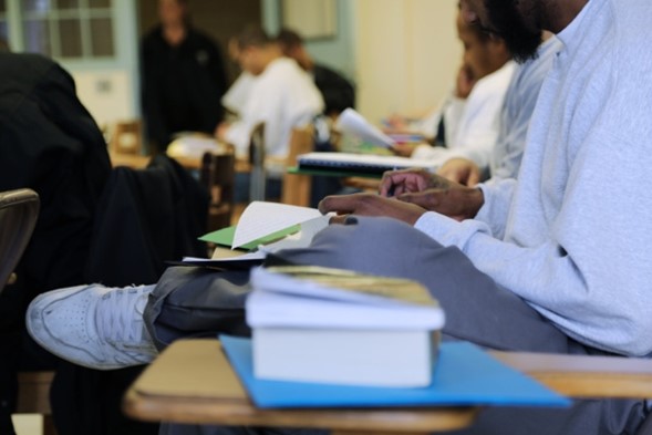 Several students sit at desks with books and writing notes in class