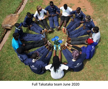 People wearing masks sit in circle with arms interlocked, feet in center