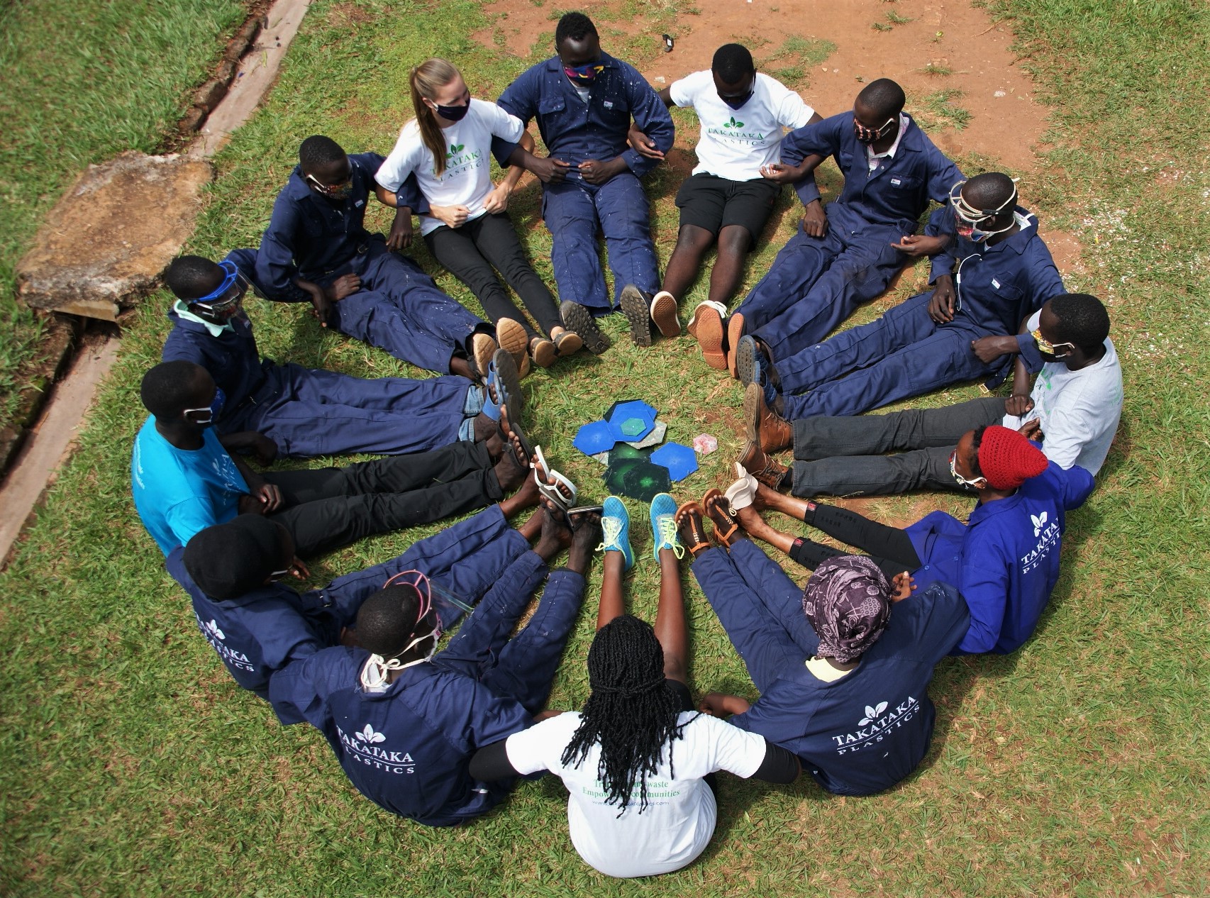 A dozen people sit in a circle with arms linked
