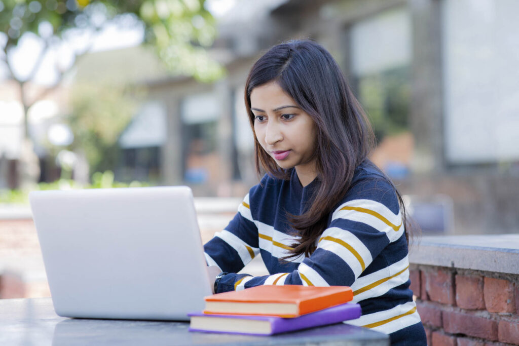 Student with books in front of laptop