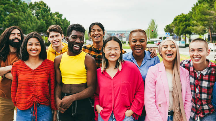 A group of young, diverse students smiling on campus.