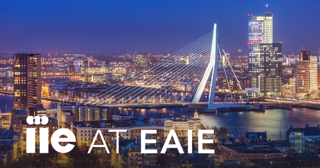 A photograph of Rotterdam, Netherlands skyline at night with the text "IIE at EAIE" in the bottom left corner in white.