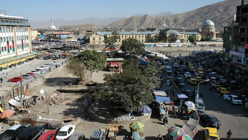 A view of central Kabul, Afghanistan showing the market, traffic, crowds of people and distant hills. Kabul Market, people, mosque, hills, central Kabul, Afghanistan